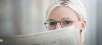 Mitarbeiterin Kathrin Guttmann mit einer Brille von Ray-Ban beim Zeitung lesen